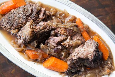 Pot Roast with carrots and onions on a white plate