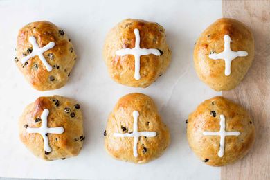 Homemade Hot Cross Buns on a surface with sugar crosses piped on top