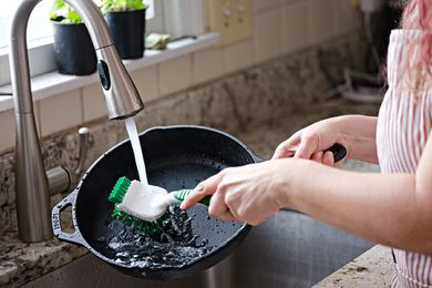 How to Clean a Cast Iron Skillet - woman scrubbing a cast iron skillet